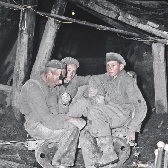 Der Arbeiter Alois Jeremias und zwei seiner Söhne sitzen auf einem Rollwagen in einem Schieferstollen, um 1960.