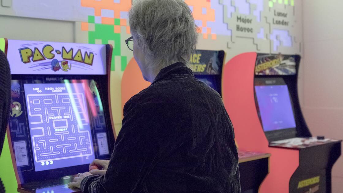 Eine Person spielt sitzend an einer alten Game-Konsole
