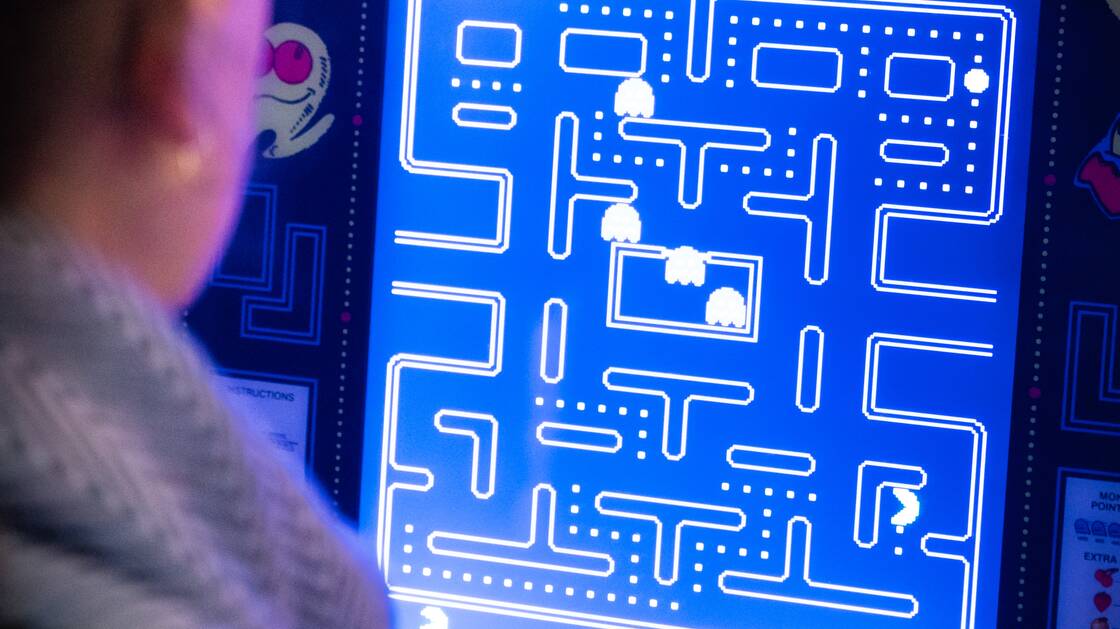 Une personne joue sur une console de jeu PacMan