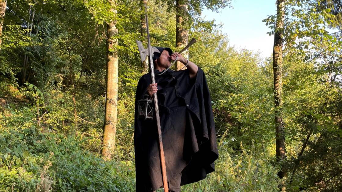Guido Schuler in Pose als Nachtwächter mit Horn inmitten eines Waldes bei Tageslicht